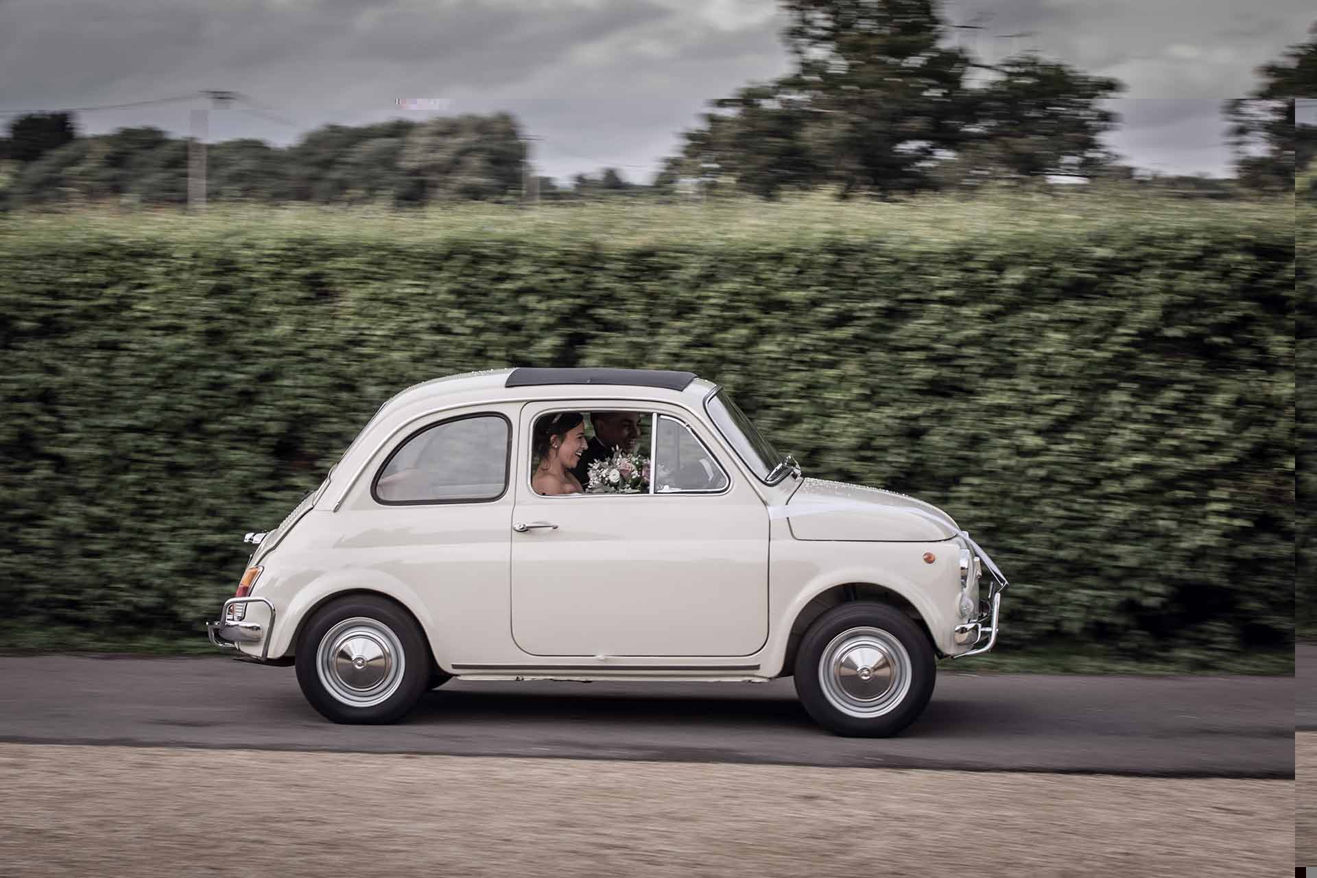 bride and groom in a Fiat 500 at a wedding